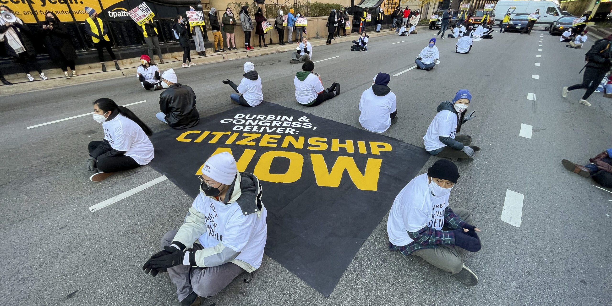 Protestors stand outside the Immigration and Customs Enforcement field office in downtown Chicago holding bullhorns and signs calling for a pathway to citizenship