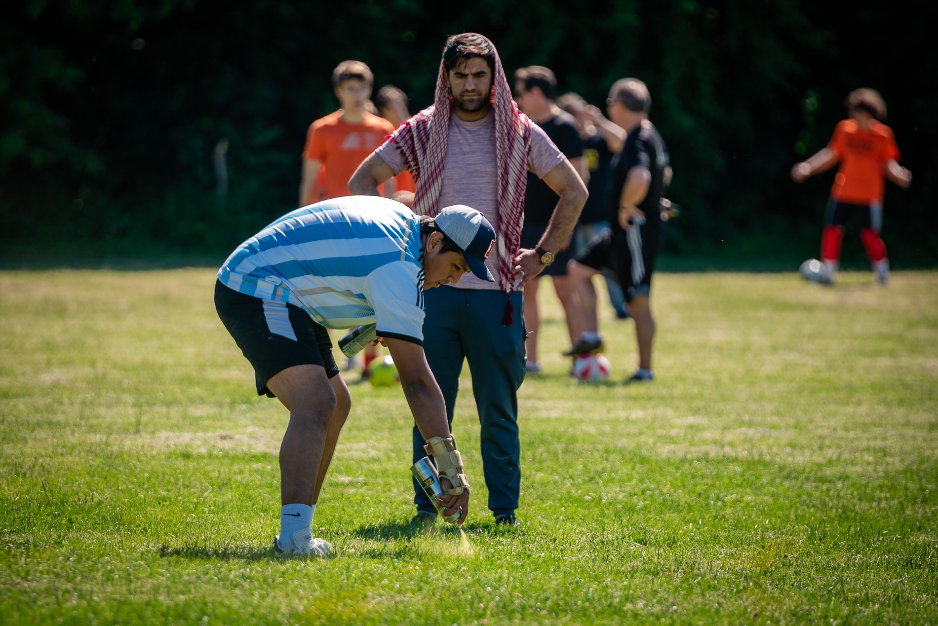 a volunteer spray paints lines for a soccer field