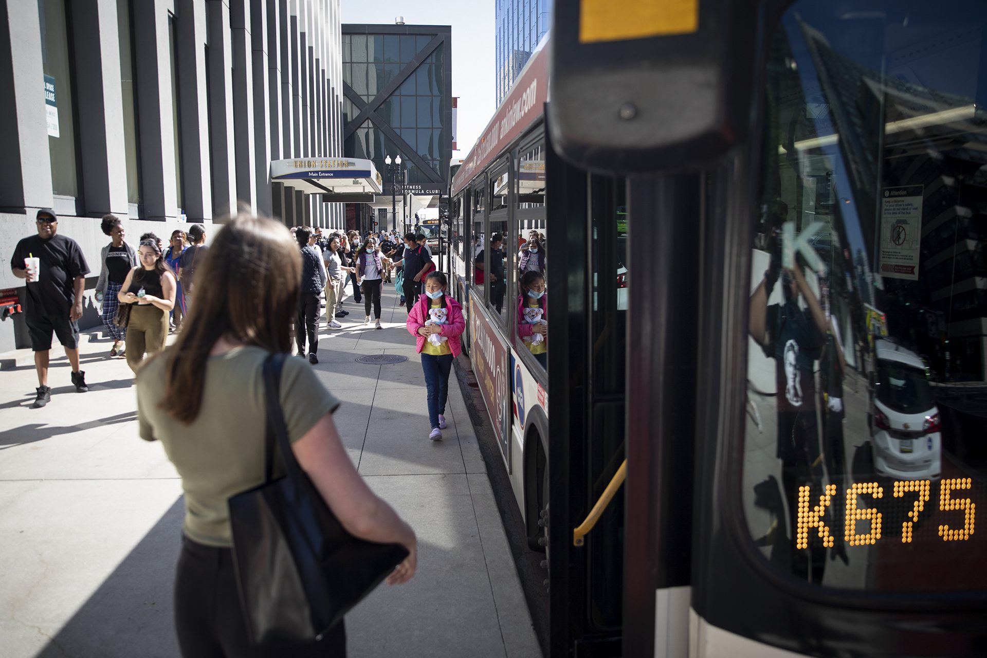 Migrants walk to a city bus after being sent to Chicago from Texas by Gov. Greg Abbott